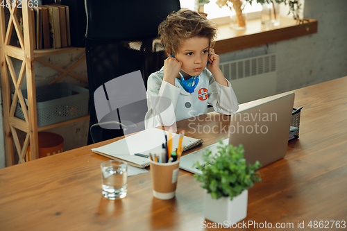 Image of Little caucasian boy as a doctor consulting for patient, working in cabinet, close up