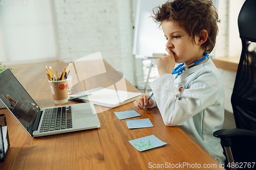 Image of Little caucasian boy as a doctor consulting for patient, working in cabinet, close up