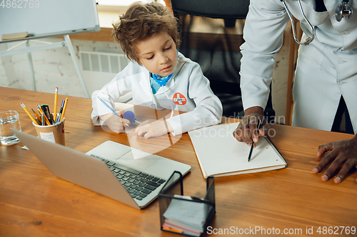 Image of Little caucasian boy as a doctor consulting for patient, working in cabinet, close up