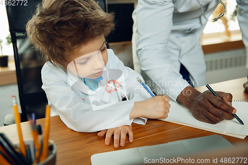 Image of Little caucasian boy as a doctor consulting for patient, working in cabinet, close up