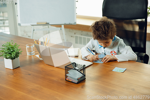 Image of Little caucasian boy as a doctor consulting for patient, working in cabinet, close up