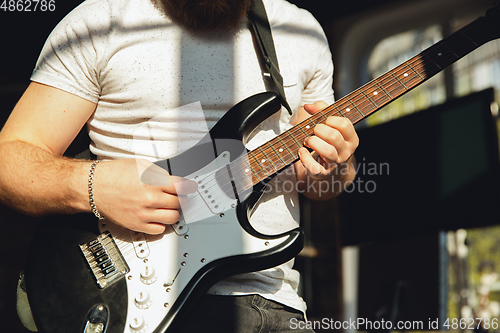 Image of Caucasian musician playing guitar during online concert at home isolated and quarantined, impressive improvising, close up