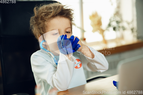 Image of Little caucasian boy as a doctor consulting for patient, working in cabinet, close up