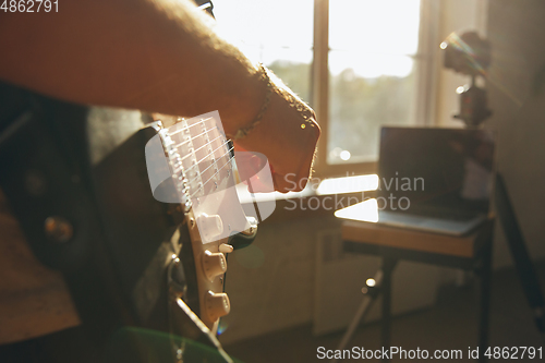 Image of Caucasian musician playing guitar during online concert at home isolated and quarantined, impressive improvising, close up