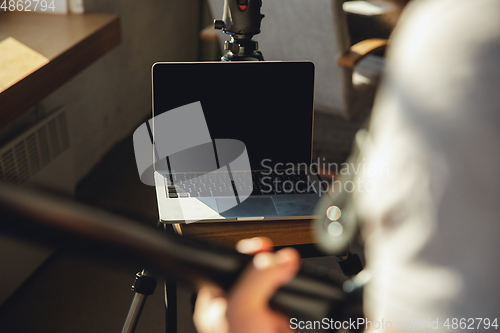 Image of Caucasian musician playing guitar during online concert at home isolated and quarantined, blank laptop screen with copyspace