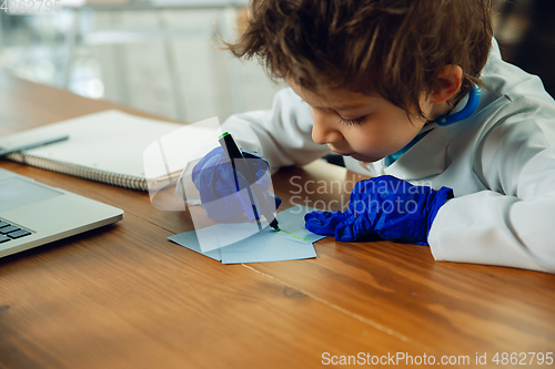 Image of Little caucasian boy as a doctor consulting for patient, working in cabinet, close up