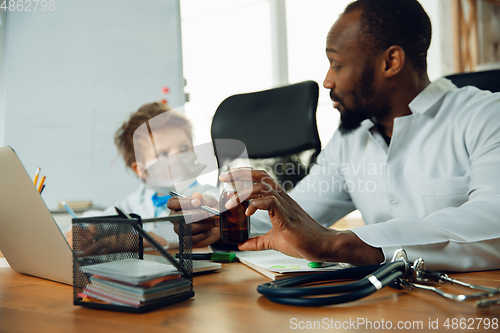 Image of Little caucasian boy as a doctor consulting for patient, working in cabinet, close up