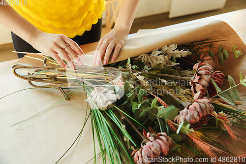 Image of Florist at work: woman shows how to make bouquet, working at home concept, close up