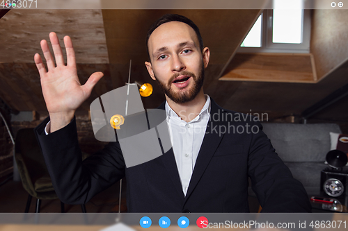 Image of Young man talking, working in videoconference with co-workers at office or living room. Online business, education during quarantine.