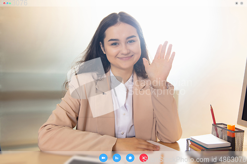 Image of Young woman talking, working in videoconference with co-workers at office or living room. Online business, education during quarantine.