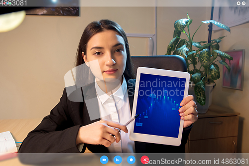 Image of Young woman talking, working in videoconference with co-workers at office or living room. Online business, education during quarantine.