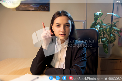 Image of Young woman talking, working in videoconference with co-workers at office or living room. Online business, education during quarantine.