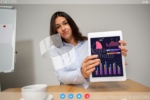 Image of Young woman talking, working in videoconference with co-workers at office or living room. Online business, education during quarantine.