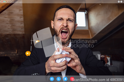 Image of Young man talking, working in videoconference with co-workers at office or living room. Online business, education during quarantine.