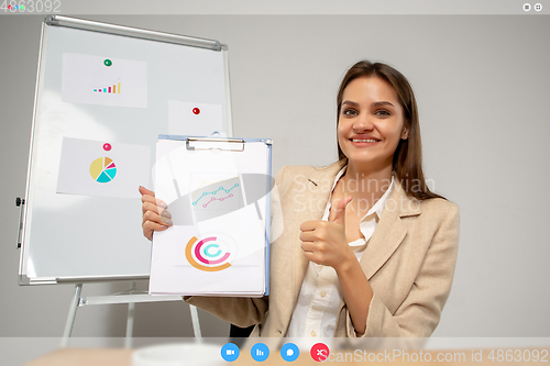 Image of Young woman talking, working in videoconference with co-workers at office or living room. Online business, education during quarantine.