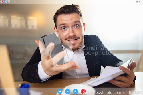 Image of Young man talking, working in videoconference with co-workers at office or living room. Online business, education during quarantine.