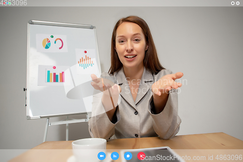 Image of Young woman talking, working in videoconference with co-workers at office or living room. Online business, education during quarantine.