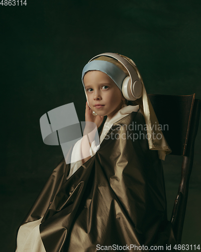 Image of Medieval little girl as a lady with a pearl earring on dark studio background. Concept of comparison of eras, childhood. Stylish creative design, art vision, new look of artwork.