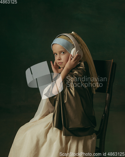 Image of Medieval little girl as a lady with a pearl earring on dark studio background. Concept of comparison of eras, childhood. Stylish creative design, art vision, new look of artwork.