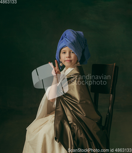 Image of Medieval little girl as a lady with a pearl earring on dark studio background. Concept of comparison of eras, childhood. Stylish creative design, art vision, new look of artwork.