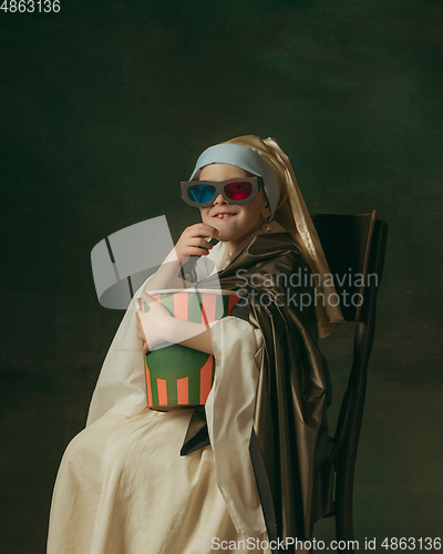 Image of Medieval little girl as a lady with a pearl earring on dark studio background. Concept of comparison of eras, childhood. Stylish creative design, art vision, new look of artwork.