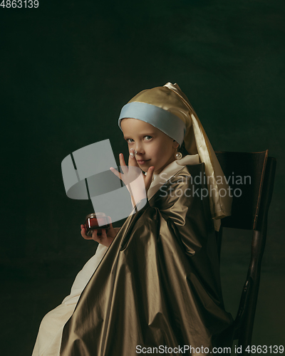 Image of Medieval little girl as a lady with a pearl earring on dark studio background. Concept of comparison of eras, childhood. Stylish creative design, art vision, new look of artwork.