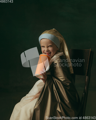 Image of Medieval little girl as a lady with a pearl earring on dark studio background. Concept of comparison of eras, childhood. Stylish creative design, art vision, new look of artwork.