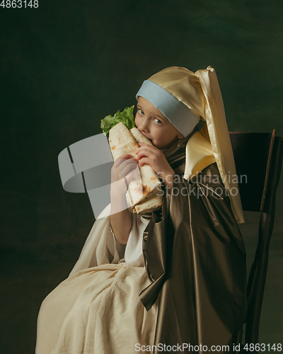 Image of Medieval little girl as a lady with a pearl earring on dark studio background. Concept of comparison of eras, childhood. Stylish creative design, art vision, new look of artwork.