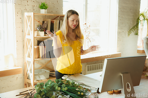 Image of Florist at work: woman shows how to make bouquet, working at home concept, choosing plants for composition