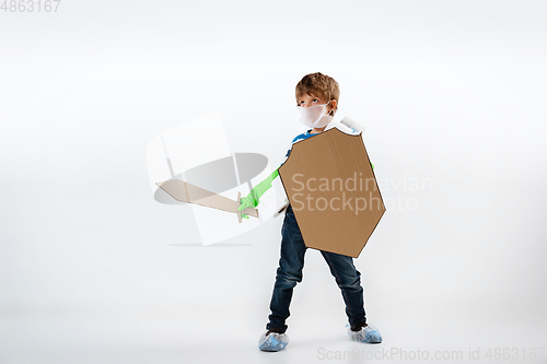 Image of Little caucasian boy as a warrior in fight with coronavirus pandemic, with a shield, a sword and a toilet paper bandoleer, protecting