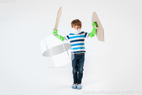 Image of Little caucasian boy as a warrior in fight with coronavirus pandemic, with a shield, a sword and a toilet paper bandoleer, attacking