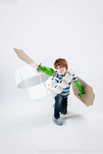 Image of Little caucasian boy as a warrior in fight with coronavirus pandemic, with a shield, a sword and a toilet paper bandoleer, attacking