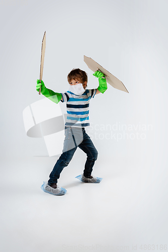 Image of Little caucasian boy as a warrior in fight with coronavirus pandemic, with a shield, a sword and a toilet paper bandoleer, attacking