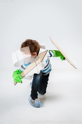 Image of Little caucasian boy as a warrior in fight with coronavirus pandemic, with a shield, a sword and a toilet paper bandoleer, attacking