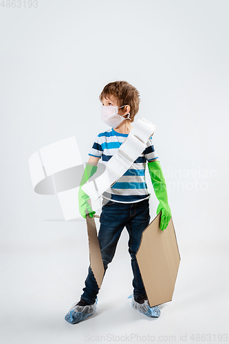 Image of Little caucasian boy as a warrior in fight with coronavirus pandemic, with a shield, a sword and a toilet paper bandoleer, preparing