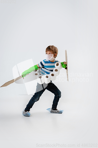 Image of Little caucasian boy as a warrior in fight with coronavirus pandemic, with a shield, a sword and a toilet paper bandoleer, protecting