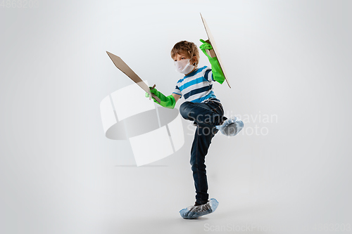 Image of Little caucasian boy as a warrior in fight with coronavirus pandemic, with a shield and sword, attacking