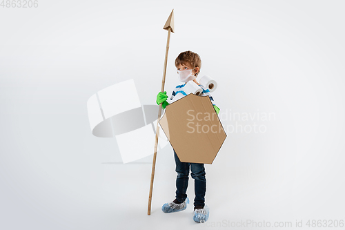 Image of Little caucasian boy as a warrior in fight with coronavirus pandemic, with a shield, a spear and a toilet paper bandoleer, attacking