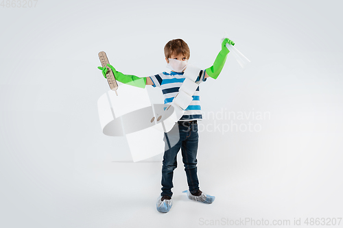 Image of Little caucasian boy as a warrior in fight with coronavirus pandemic, with a face mask, a thermometer, sanitizer and a toilet paper bandoleer