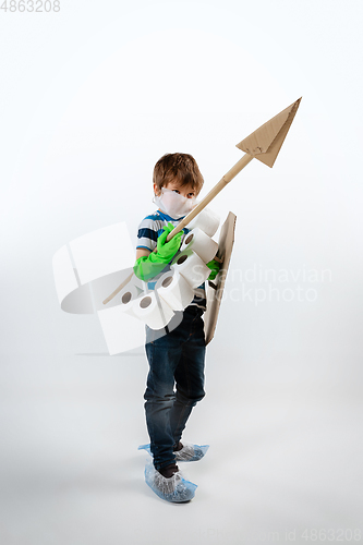 Image of Little caucasian boy as a warrior in fight with coronavirus pandemic, with a shield, a spear and a toilet paper bandoleer, attacking