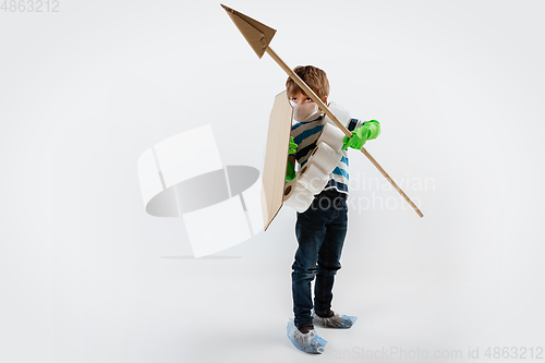 Image of Little caucasian boy as a warrior in fight with coronavirus pandemic, with a shield, a spear and a toilet paper bandoleer, attacking