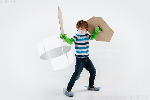Image of Little caucasian boy as a warrior in fight with coronavirus pandemic, with a shield, a sword and a toilet paper bandoleer, protecting