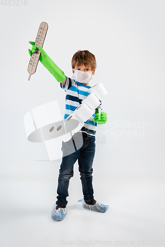 Image of Little caucasian boy as a warrior in fight with coronavirus pandemic, with a face mask, a thermometer, sanitizer and a toilet paper bandoleer