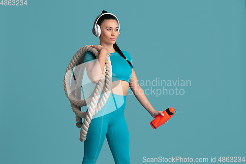 Image of Beautiful young female athlete practicing on blue studio background, monochrome portrait