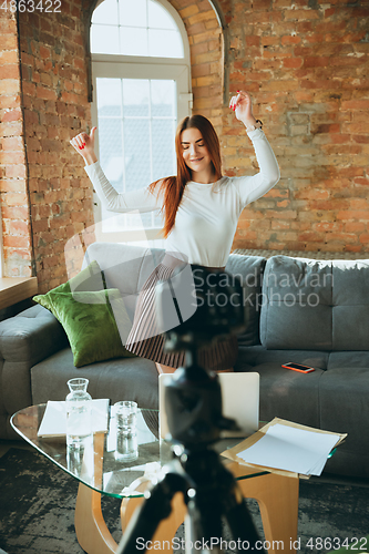 Image of Caucasian woman singing during online concert at home isolated and quarantined, impressive improvising, dancing