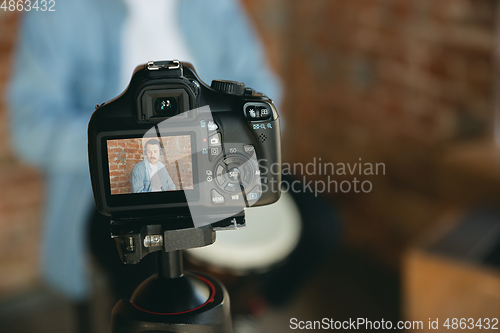 Image of Caucasian musician playing hand drum during online concert at home isolated and quarantined, focus on camera