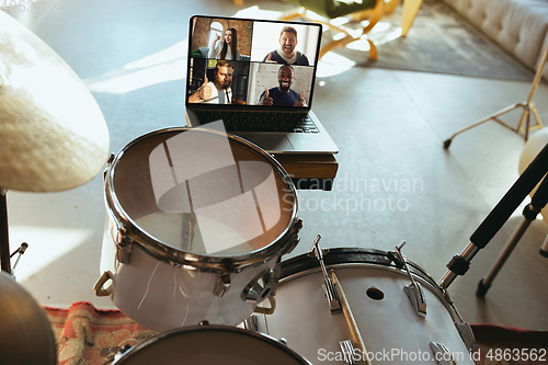 Image of Caucasian musician playing drumms during online concert or sound-check with the band at home isolated and quarantined, focus on laptop