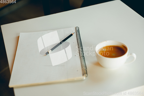 Image of White cup of hot coffee and white sketch book on the table - working process, inspiring workplace