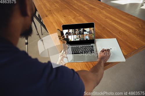 Image of African-american musician playing saxophone during online concert or sound-check connected with the band at home isolated and quarantined