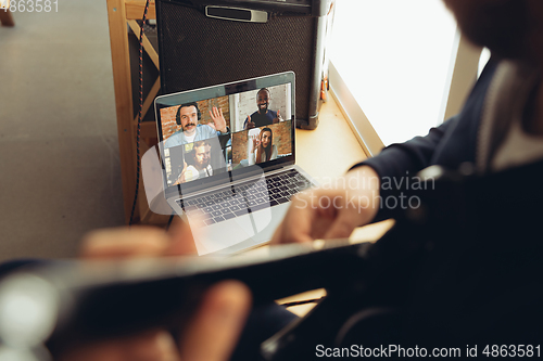 Image of Caucasian musician playing guitar during concert at home isolated and quarantined, cheerful improvising with the band connected online